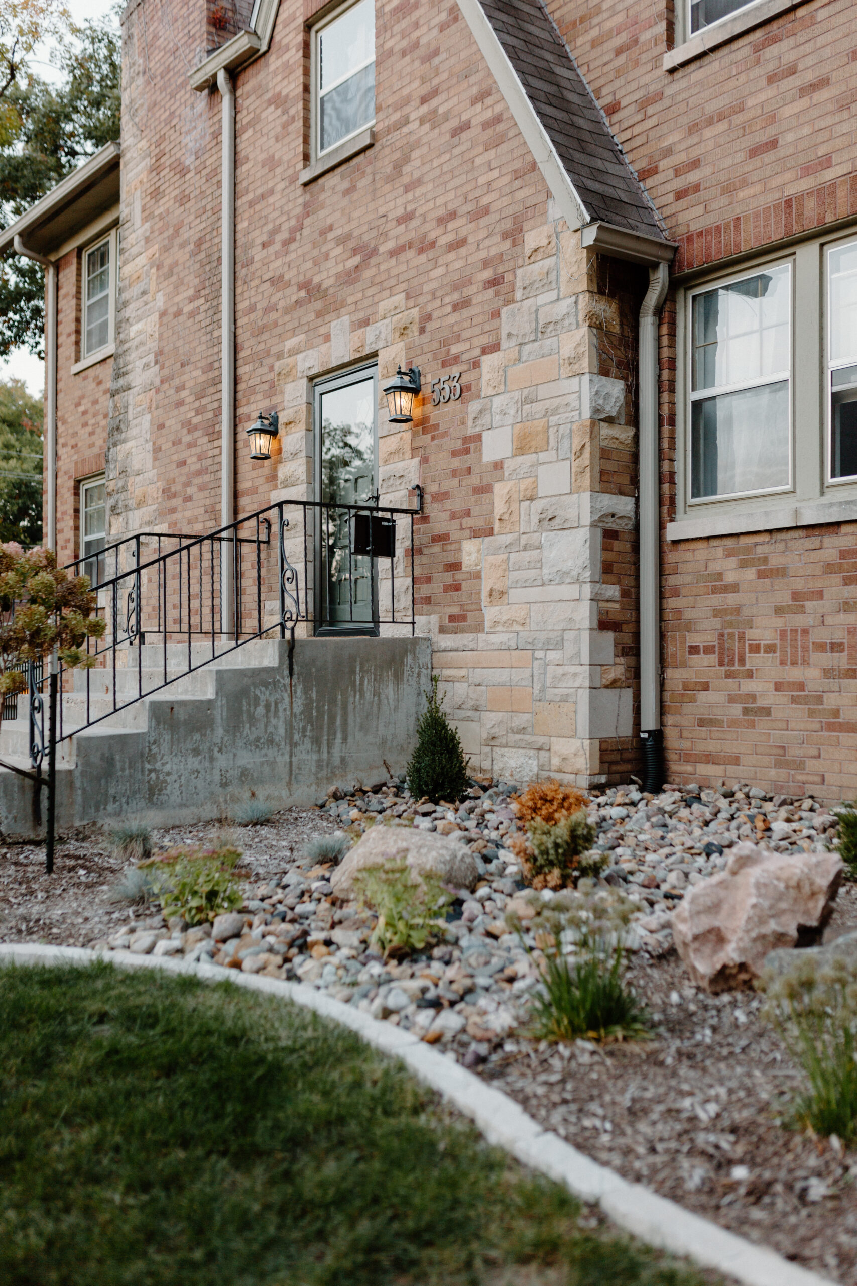 Rock garden bed in front of a brick and stone house. Central Iowa Landscape Installation