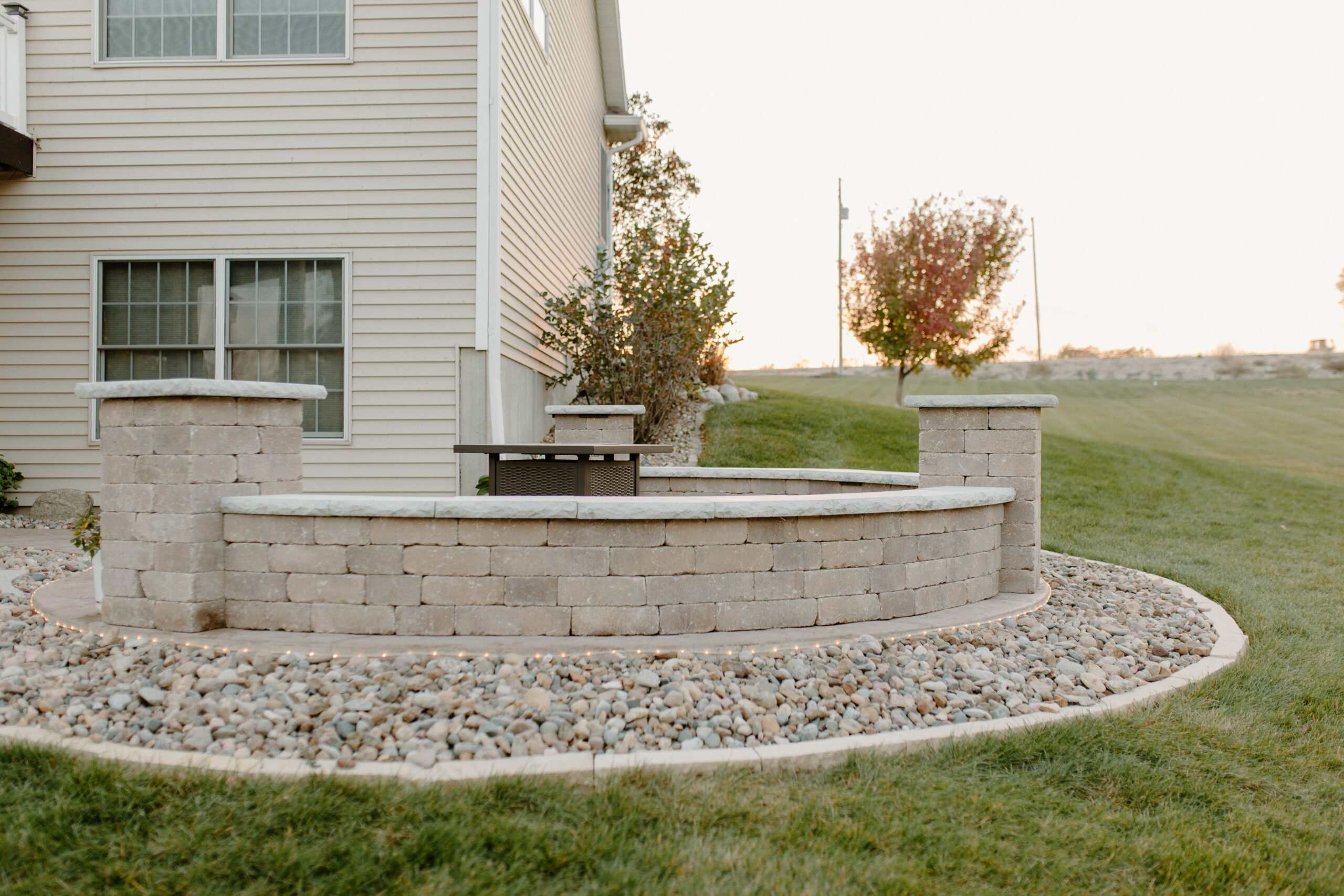 Seating wall around a firepit with rock bed surround. Creative Nature Iowa Landscape Design and Installation
