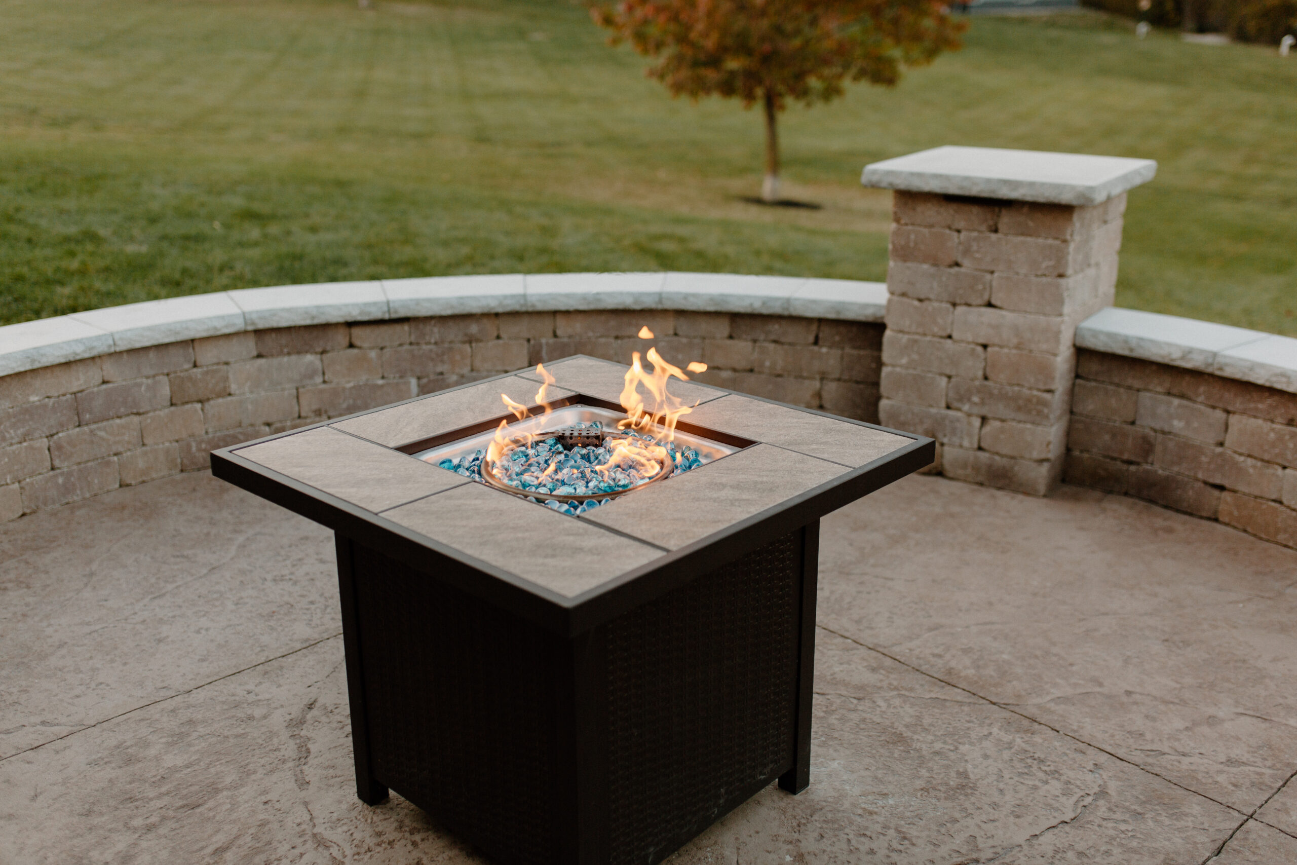 fire going in a fire pit on a patio with a stone seating surround - Creative Nature Iowa