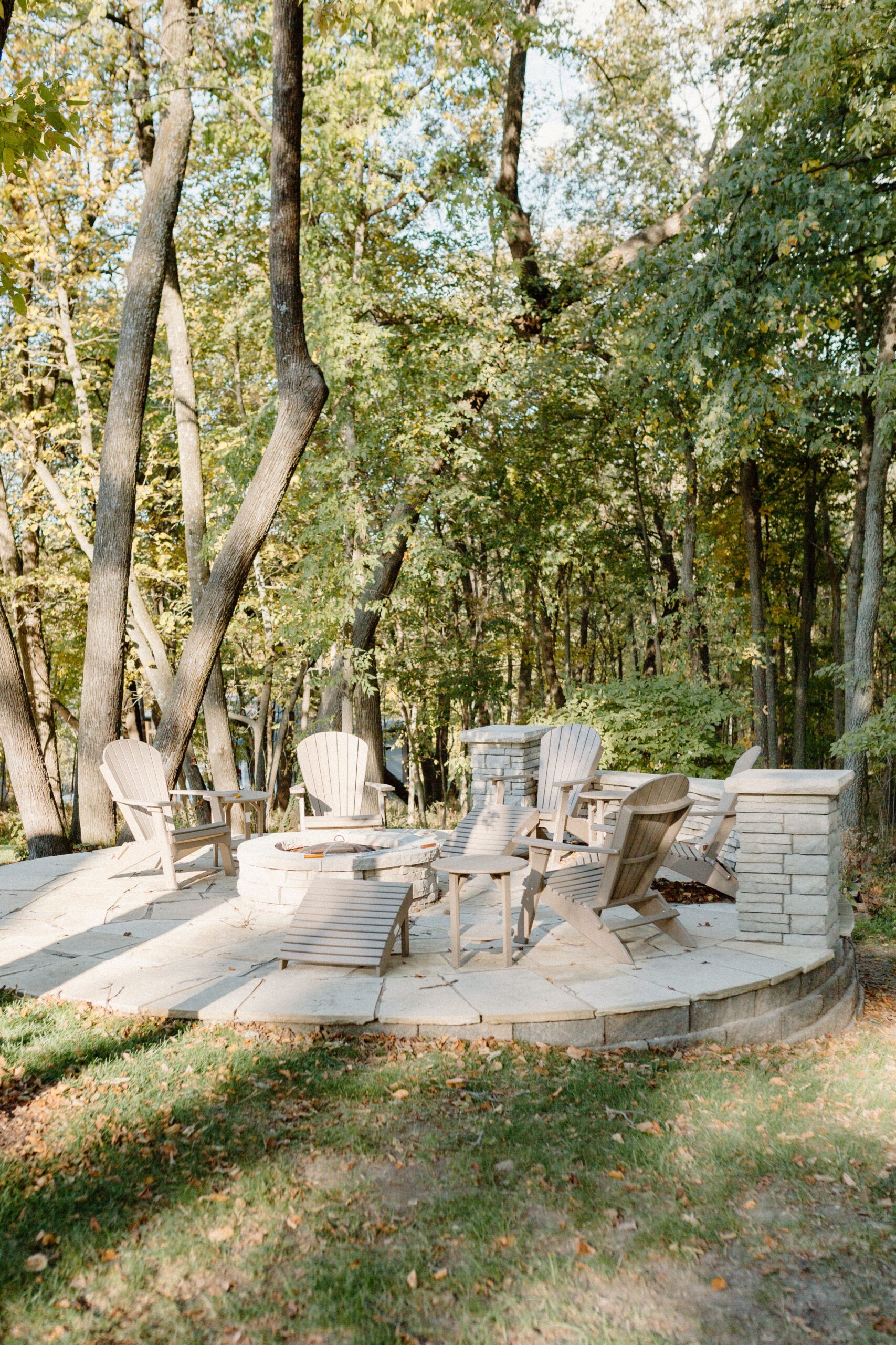 Stone firepit with stone patio and bench seating in a wooded area - Creative Nature Iowa